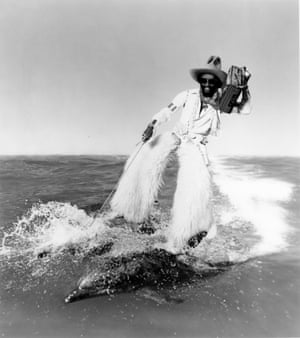 Artwork of George Clinton riding on the back of a pair of dolphins while dressed as a cowboy which was used to publicise Parliament's 1978 album Motor Booty Affair