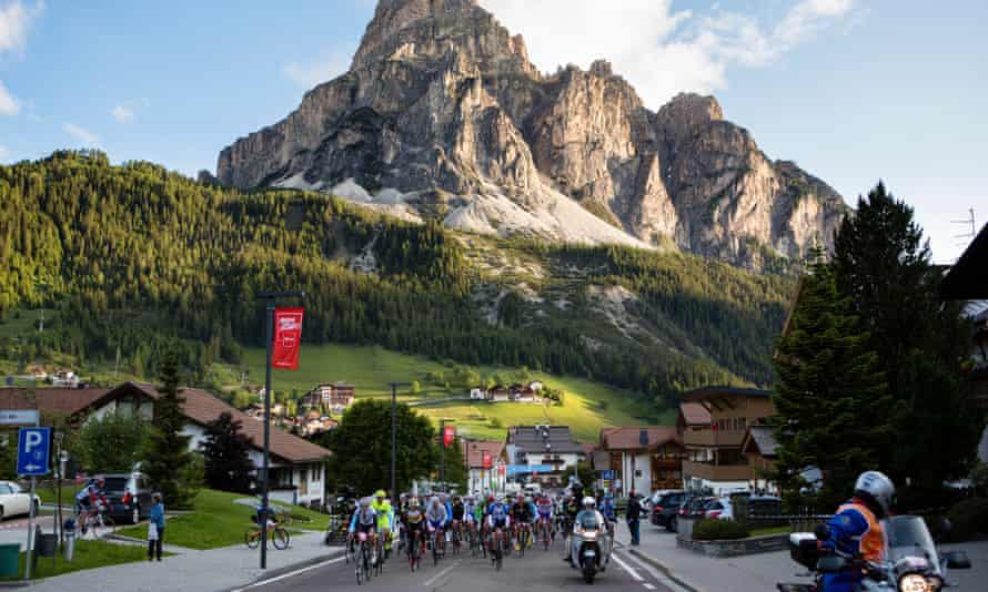 A group of cyclists ride by a mountain during the Maratona dles Dolomites race, Italy