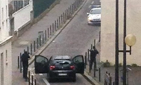 Armed gunmen face police officers near the offices of the French satirical newspaper Charlie Hebdo, in Paris.