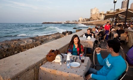 A young couple enjoy a sheesha at a seafront cafe.