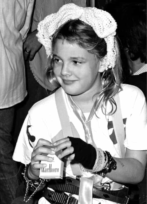 Una giovane Drew Barrymore con in mano un pacchetto di sigarette