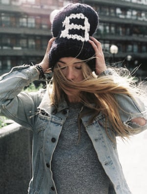 A woman holding her Count On Me Beanie on her head in the wind