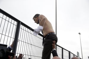 Broseta clambers over a gate after having his shirt torn off his back
