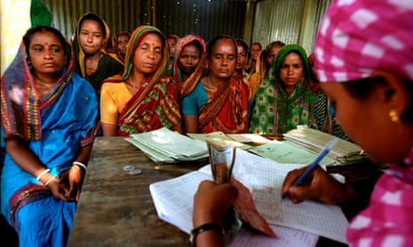Women in India sit around a desk as another woman counts money
