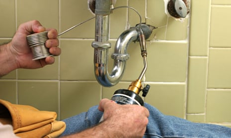 A plumber using a welding torch to solder pipe in the bathroom