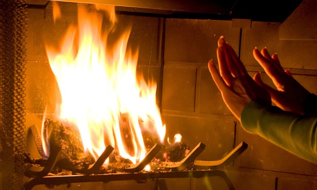 A woman warming her hands by a roaring fire