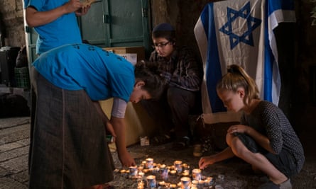Children pray and light candles at the site of rabbi Nechamia Lavie’s killing