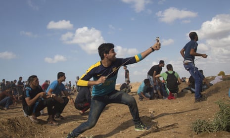 A Palestinian protester hurls stones at Israeli soldiers during clashes on the Israeli border with Eastern Gaza.