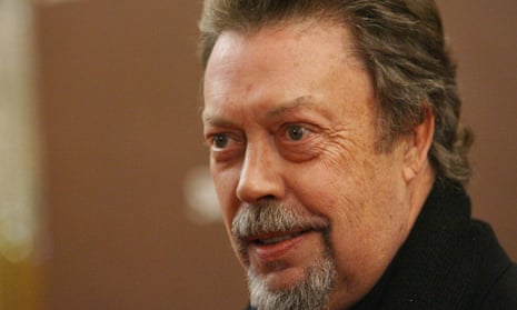 Head and shoulders shot of Tim Curry in a black roll-neck sweater.