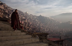 A Tibetan Buddhist nun walks passed dwellings on her way to a chanting session