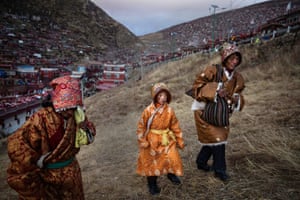 A Tibetan Buddhist nomad family walks on a hillside follwing prayers