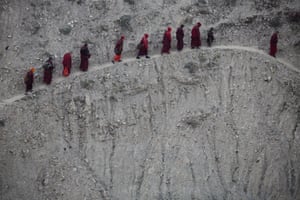 Monks and nuns walk up a steep hill path back to their dormitory after attending a daily chanting session