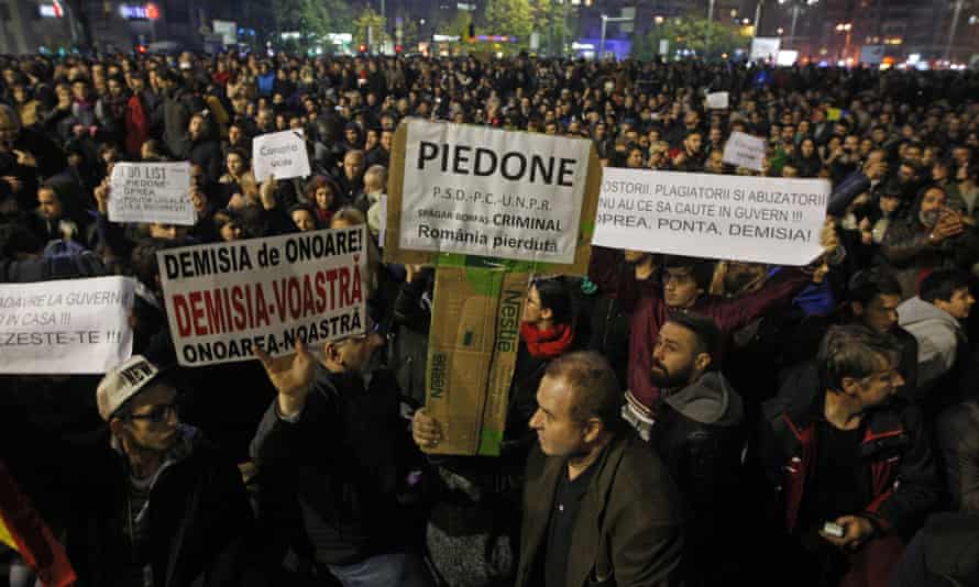 Romanians hold placards calling for the resignations of mayor Cristian Popescu Piedone, minister Gabriel Oprea and prime minister Victor Ponta.
