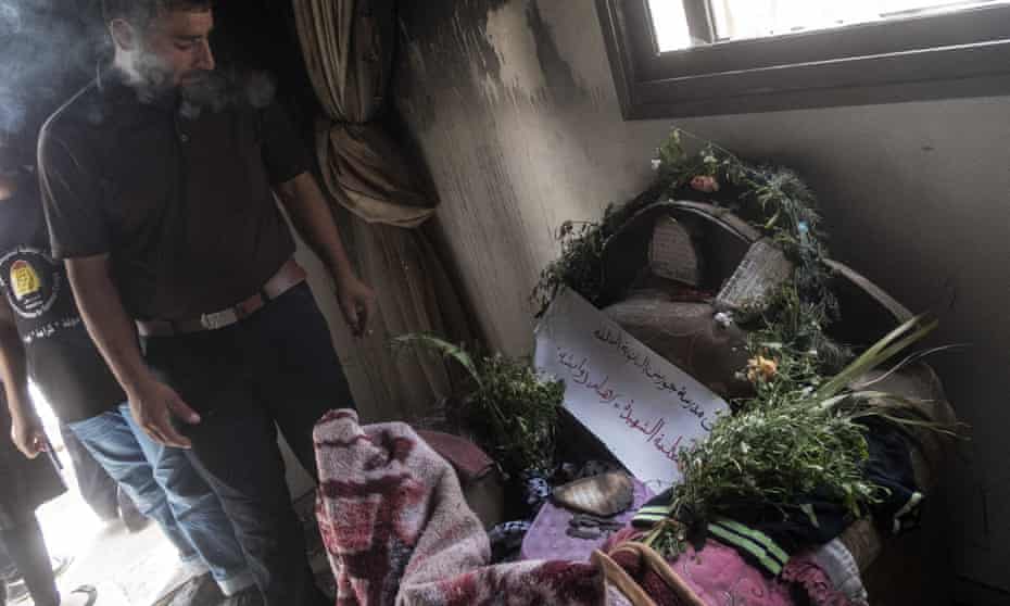 A mourner examines the cot in which 18-month-old Ali Dawabshe died in an arson attack in July