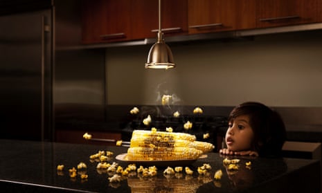Boy (3-4) watching corn become popcorn under light
