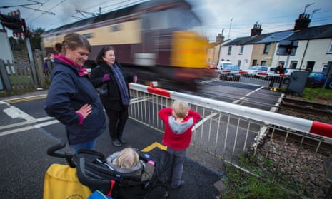 A level crossing at Cardinalls Road, Stowmarket, Suffolk.Rosie Carter (blue scarf) and Kym Halladay with Georgia (in buggy) and Harry age 4.Photograph: Graham Turner. trainstransportrailwaycrossing