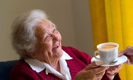 elderly woman being handed a cup of tea