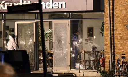 Police examine the bullet-marked cafe where the first attack took place.