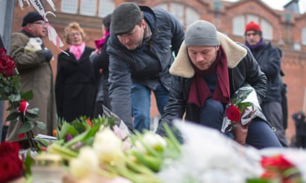 People place flowers close to the scene of the cafe shooting in Oesterbroin in Copenhagen.