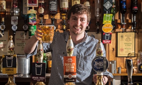 Peter Tiley, landlord of the Salutation Inn in Ham, Gloucestershire, holding up a pint of beer behind the bar