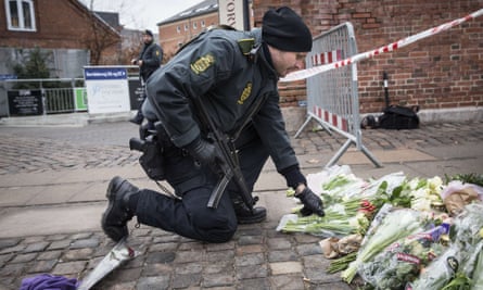 A police officer lays flowers outside the main Synagogue in Copenhagen following the fatal attacks in the Danish capital