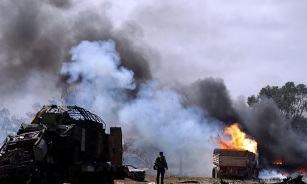 A Libyan rebel fighter looks at burning vehicles belonging to forces loyal to Gaddafi after an air strike by coalition forces in 2011.