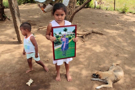 The girl holds a photograph of her grandfather who worked as a sugarcane cutter and died nine years ago of chronic renal failure.