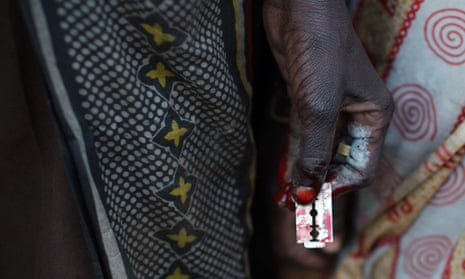 A woman holds a razor blade after performing a circumcision on four girls in a village in Kenya