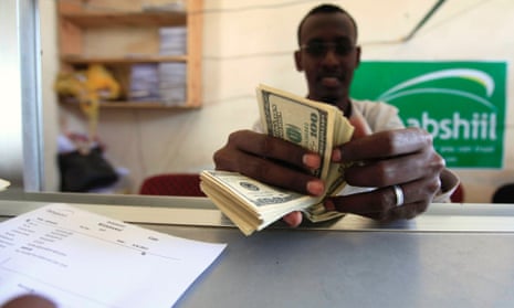 A worker counts U.S. dollars as he serve a customers at a Dahabshiil money transfer office in "Kilometer Five" street of Soobe village, southern Mogadishu, in this May 8, 2013 file photo. About 40 percent of all Somali families rely on remittances from another country, and the estimated annual total of $1.3 billion is more than all foreign aid and investment in Somalia combined.