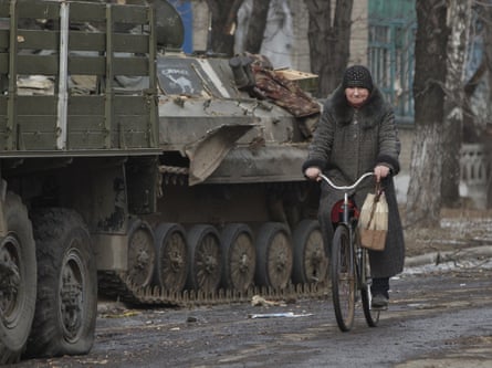 A resident rides a bicycle passing by an armoured vehicle in Debaltseve.