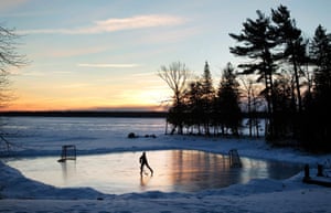 A youth plays pond hockey as the sun rises on Pigeon Lake in the region of Kawartha Lakes Ontario, Canada
