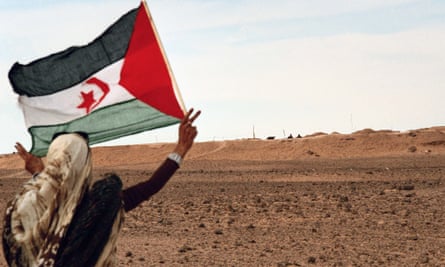 A woman with a Saharawi flag near the so-called Moroccan Wall, a defensive fortification within Western Sahara.