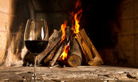 a glass of red wine infront of a fire