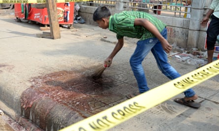 A man cleans up blood at the site where Avijit Roy was killed.