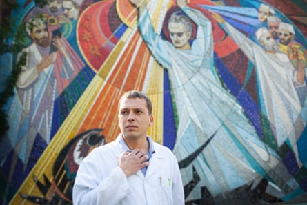 Andrei Semivolos stands outside the institute, in front of a Soviet mural depicting doctors fighting cancer. Photo by Joel van Houdt   longread ukraine