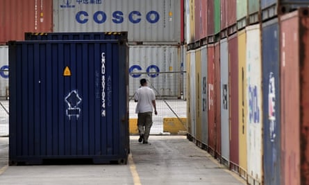 A man walks between containers at the port of Piraeus, near Athens.