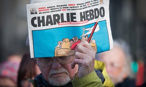 A man holds up a copy of Charlie Hebdo at a Bristol vigil