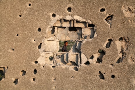 A child looks through a hole in the wall of his home after Israel’s attack on Gaza in 2013. Majdi Fathi/NurPhoto/Rex