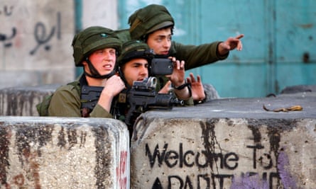 An Israeli soldier photographs clashes with Palestinian stone-throwers in the West Bank city of Hebron on March 6, 2015.
