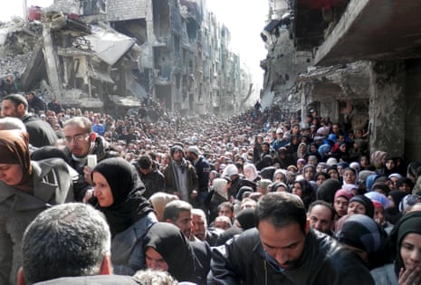 Residents of the besieged Palestinian camp of Yarmouk, queuing to receive food supplies, in Damascus, Syria, in 2014. A new UN-backed report paints a devastated picture of the effect of war on a population.