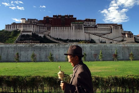 A pilgrim rotates a prayer wheel outside of Potala Palace in Lhasa, Tibet.