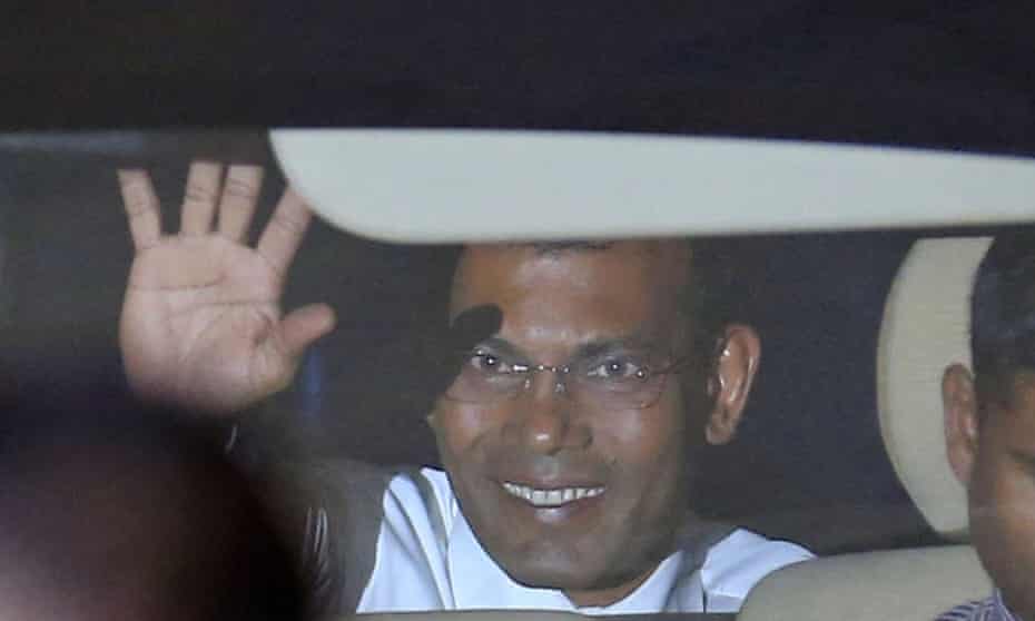Mohamed Nasheed waves to reporters from inside a car outside the court after a three-judge panel pronounced his verdict.