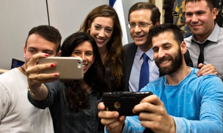 Yitzhak Herzog (third from right) poses for selfie photographs with supporters on Monday.