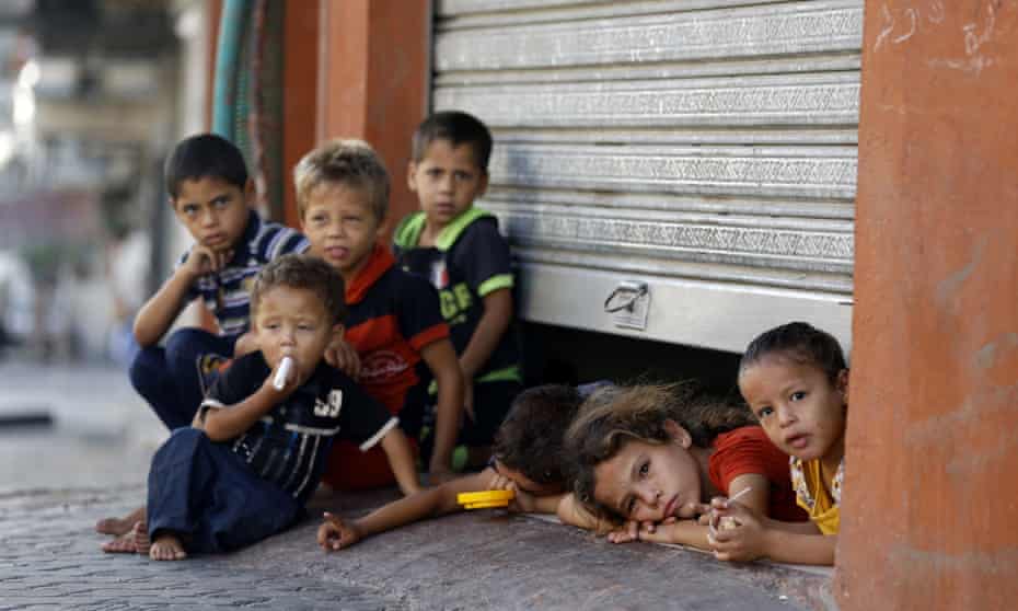 Displaced Palestinian children peak from under a shop door, where their family is taking shelter in Gaza City in July 2014.