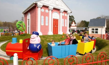 Families waving in a train circling a house in Peppa Pig World, Paultons Park in Hampshire
