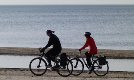 Two cyclists on the sand at Jurmala beach in Latvia