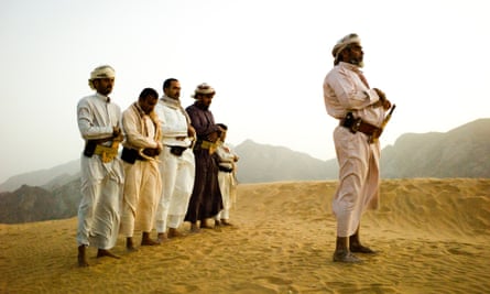 A tribal sheikh and his men praying in the dunes of Marib province