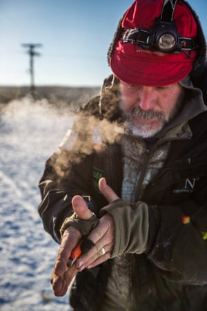 Musher Scott Janssen warms up his lighter so he can light a cooking fire at the Ruby checkpoint