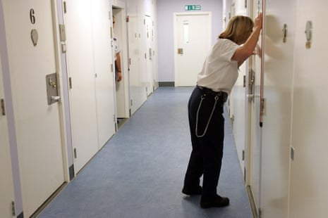 A detention officer looking through a cell door observation hole, at the Colnbrook immigration removal centre at Heathrow Airport, where staff are struggling to cope with soaring numbers of dangerous and vulnerable detainees