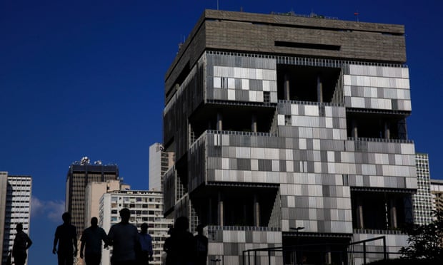 Pedestrians walk past the headquarters building of Petroleo Brasileiro SA (Petrobras) in Rio de Janeiro, Brazil, on Thursday. Feb. 12, 2015. The corruption probe at Brazil's state-run oil producer is becoming a greater threat to the ruling Workers' Party than any scandal during its 12-year ascendancy.